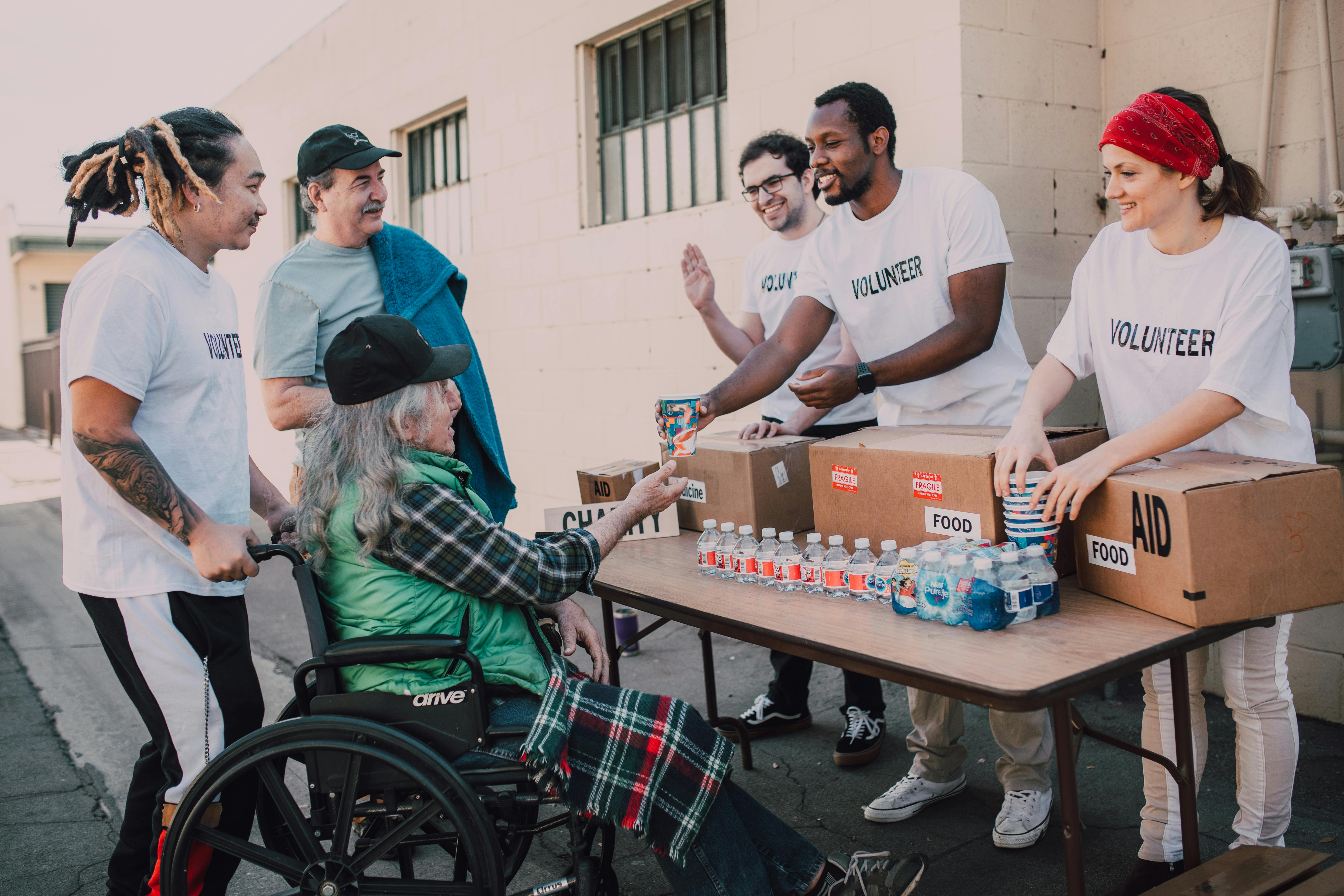 A Group of Volunteers Assisting an Elderly Person on a Black Wheelchair For Charity - Photo by RDNE Stock Project
